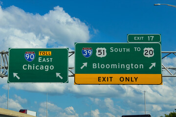 midwest travel banner.  a highway sign for Interstate 90 (I-90) toward Chicago and a sign toward Bloomington. Transportation passenger view design element © mailcaroline