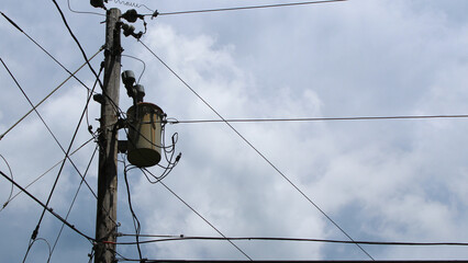 looking up at a distribution transformer isolated against the sky. electrical power and energy...