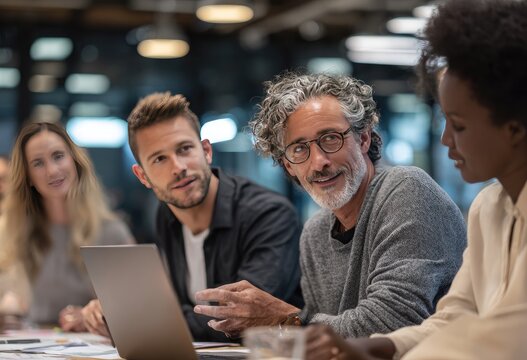 A diverse group of professionals engages in a focused discussion around a table in a modern office setting, showcasing collaboration and teamwork