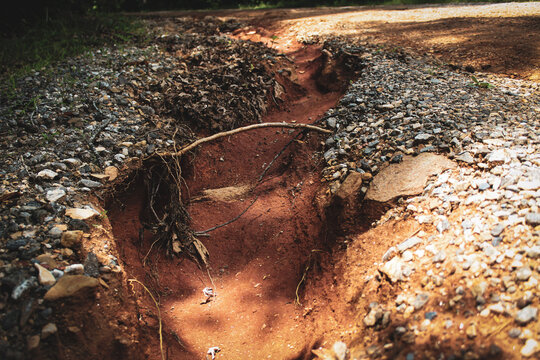 close-up of a channel formed on a hillside road caused by fast falling rain. ultisol red clay soil erosion background
