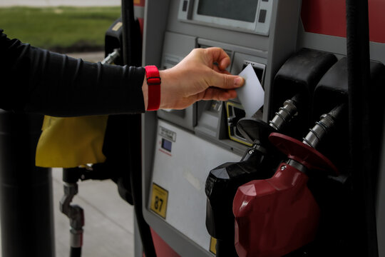a person tapping a credit card onto a payment reader at a fueling station gas pump. transportation, economy, and industry design element.