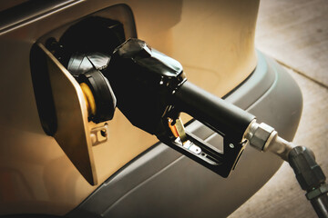close-up of refueling a vehicle at a gas station. the fuel nozzle and the vehicle's fuel tank...