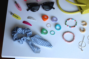 Green bag, various colorful jewelry, sunglasses, hair accessories and colorful make up on white background. Selective focus.