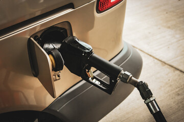 gasoline pump nozzle inserted into a vehicle's fuel tank during refueling at a gas station