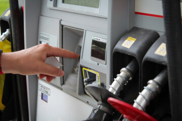 a person entering numbers on a fuel pump station keypad while holding a payment card before pumping...