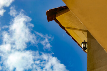 low angle view of a terra cotta clay roofline and a wall, in warm, earthy tones. tropical or...