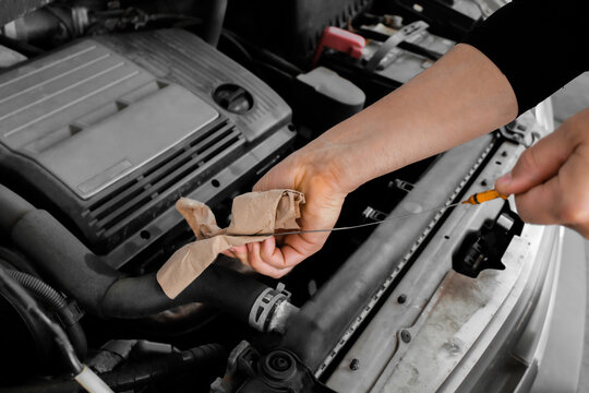 close-up of a person checking the engine oil level in a car using a dipstick. automotive or transportation design element