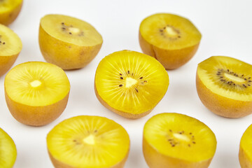 Yellow gold kiwi fruit halves arranged artistically on a clean white surface, showcasing vibrant...