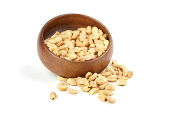 Roasted salted peanuts in a wooden bowl, scattered on a white background, showcasing their crunchy...