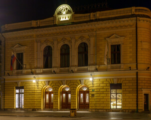 Illuminated historic building in Ljubljana at night with classical facade