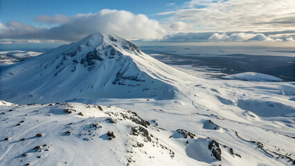 Snowy mountain peak under a cloudy sky with a view of the distant ocean and landmasses beyond - ai generated