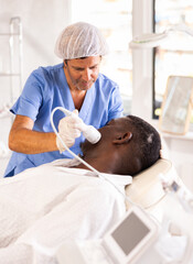 Experienced cosmetologist performing cryotherapy procedure on african american man using cooling...