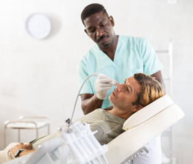 European man lying on couch during skin purificating procedure with air hydrogen-oxygen cleaning...
