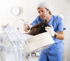 Professional male aesthetician administering high frequency ultrasound facial procedure on adult...