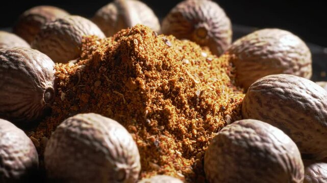 Whole nutmegs and ground nutmeg powder, close-up detail