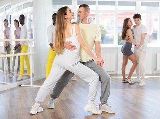 Girl in sport clothes dress dances incendiary tango with male partner during choreography lesson....