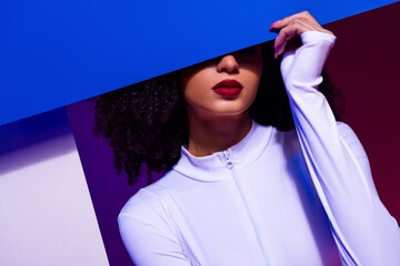Trendy young woman in a fashionable white jumpsuit with vibrant background lighting, presenting...