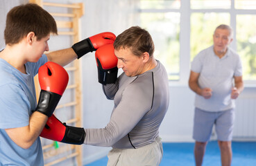 Adult man with partner in boxing gloves boxing in gym