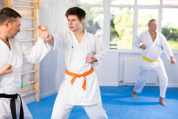 Young guy and his coach practice punches in karate sparring
