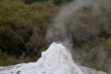 A powerful geyser erupts with a towering column of steam and water, set against a misty, dramatic...