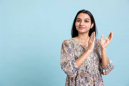 Indian cheerful girl clapping hands and celebrating a milestone in studio, proud and satisfied with an achievement. Young adult smiling and applauding, saying congratulations for victory.