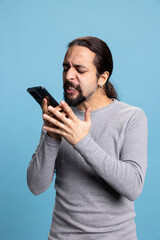 Young person having a furious reaction after receiving bad news on phone call, getting angry and...