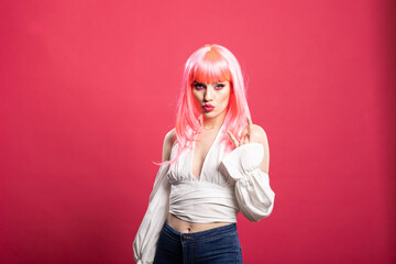 Beautiful caucasian woman with pink hair and pursed lips, flashing playful rock hand gesture....