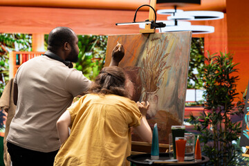 Team of skilled artist collaborating on a rustic painting in art studio, using creative painting...