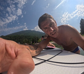 Tourist turns on an action cam before a hike on a stand up paddle board in the lake of Levico in...