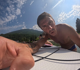 Tourist turns on an action cam before a hike on a stand up paddle board in the lake of Levico in...