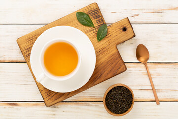 Cup of tea with dry and fresh leaves on wooden background, top view