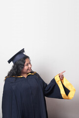 Young brunette Latina woman wearing a cap and gown celebrates her graduation and the completion of...