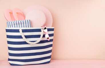 Blue beach bag with summer accessories on wooden table