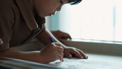 Asian boy concentrating on drawing with colorful felt tip pens