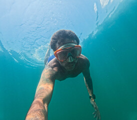Man swims underwater in apnea moving with elegance. The man is forty years old, of Caucasian...