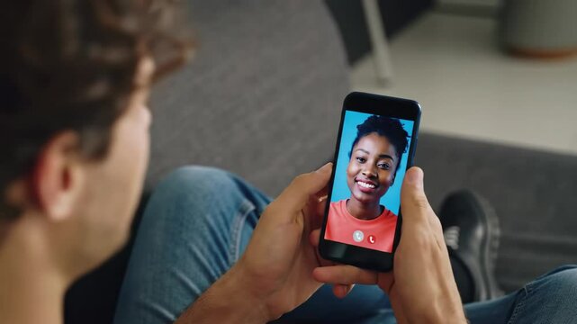 Young man video calling with friend using mobile phone at home - Powered by Adobe