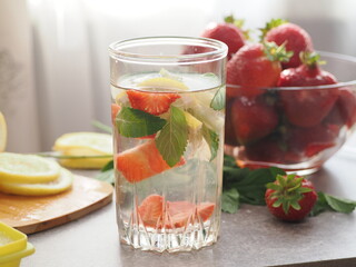 woman making refreshing homemade lemonade detox drink or cocktail summer with ice. Refreshing vibrant summer drinks with lemon, strawberry and mint and colorful straws on the table