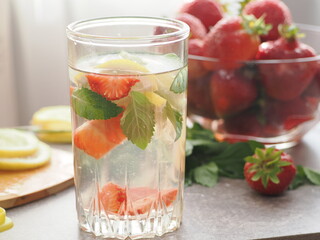 woman making refreshing homemade lemonade detox drink or cocktail summer with ice. Refreshing vibrant summer drinks with lemon, strawberry and mint and colorful straws on the table