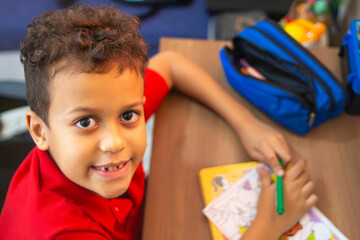 Smiling boy studying and coloring at home