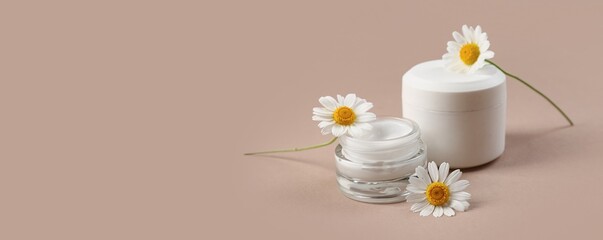 Jars of natural cream and chamomile flowers on beige background with space for text