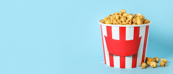 Bucket with tasty popcorn on blue background
