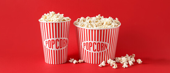 Buckets with tasty popcorn on red background