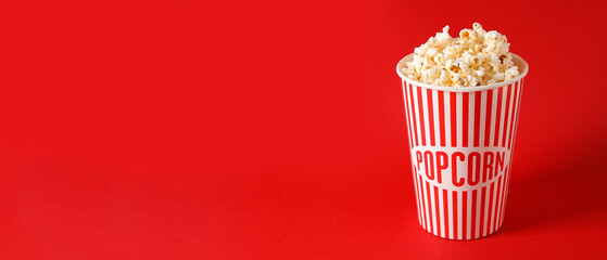 Bucket with tasty popcorn on red background