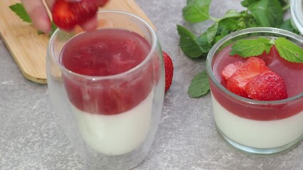 Vanilla panna cotta with strawberry layer in a small portioned vase and fruit pieces in wineglasses. Delicious Italian dessert. low calorie dessert healthy eating diet. woman cooking at home