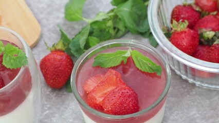 Vanilla panna cotta with strawberry layer in a small portioned vase and fruit pieces in wineglasses. Delicious Italian dessert. low calorie dessert healthy eating diet. woman cooking at home
