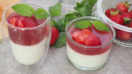 Vanilla panna cotta with strawberry layer in a small portioned vase and fruit pieces in wineglasses. Delicious Italian dessert. low calorie dessert healthy eating diet. woman cooking at home