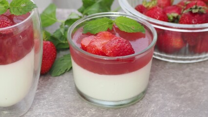 Vanilla panna cotta with strawberry layer in a small portioned vase and fruit pieces in wineglasses. Delicious Italian dessert. low calorie dessert healthy eating diet. woman cooking at home