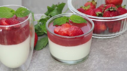 Vanilla panna cotta with strawberry layer in a small portioned vase and fruit pieces in wineglasses. Delicious Italian dessert. low calorie dessert healthy eating diet. woman cooking at home