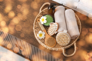 Wicker tray with massage body brushes and towels on chest of drawers in bathroom, top view