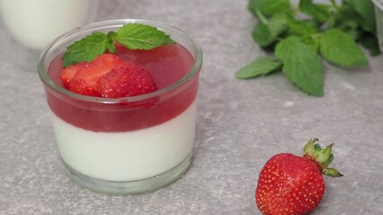 Vanilla panna cotta with strawberry layer in a small portioned vase and fruit pieces in wineglasses. Delicious Italian dessert. low calorie dessert healthy eating diet. woman cooking at home